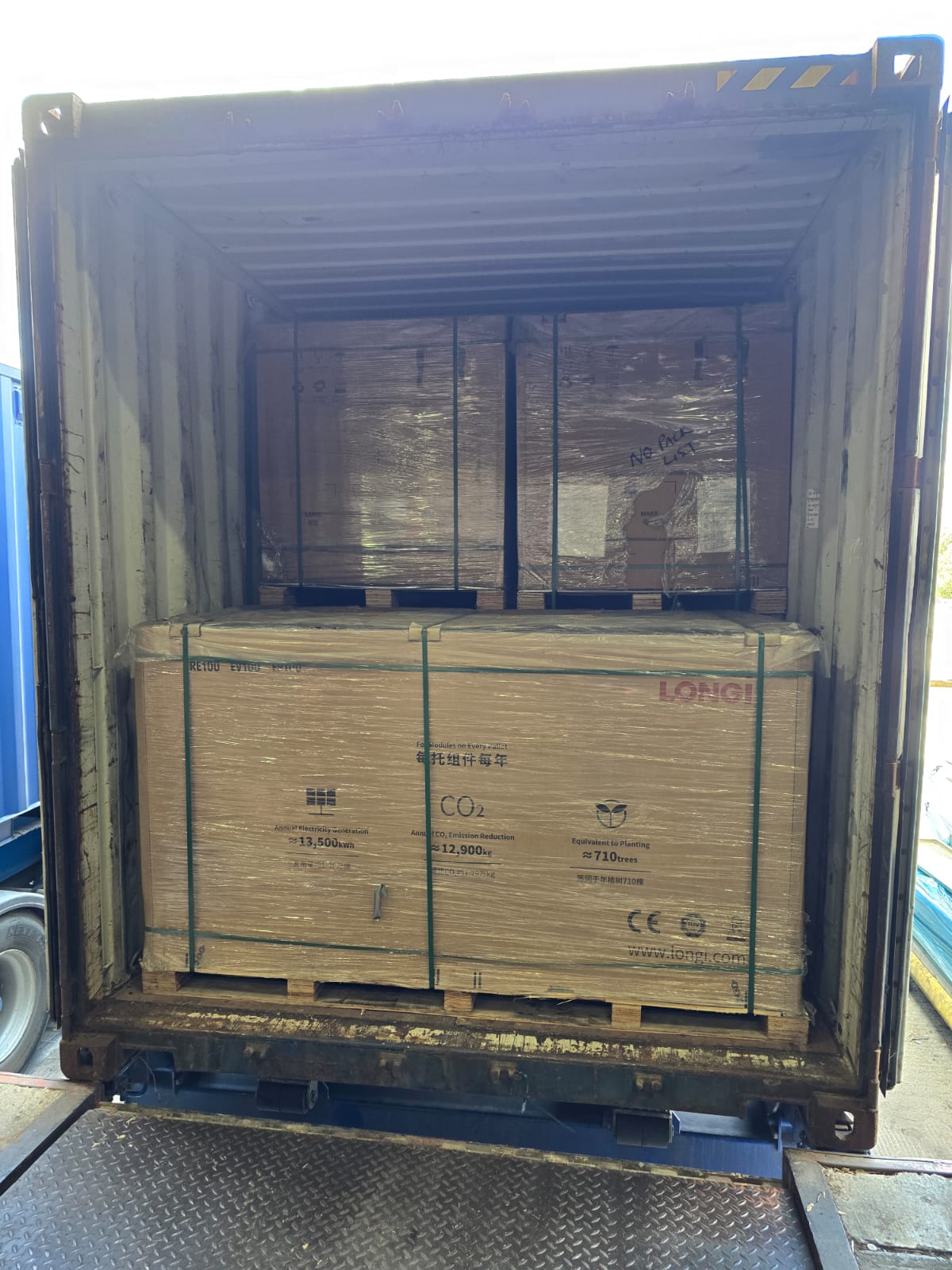 Shipping container being loaded with palletized solar panels for export